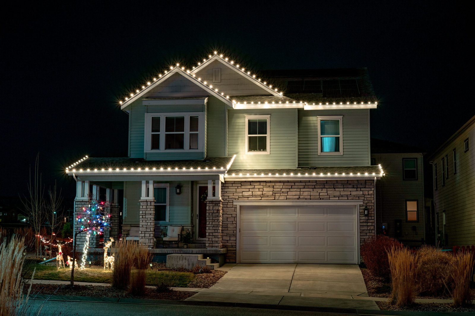 Holiday-decorated two-story suburban home with festive roofline lighting